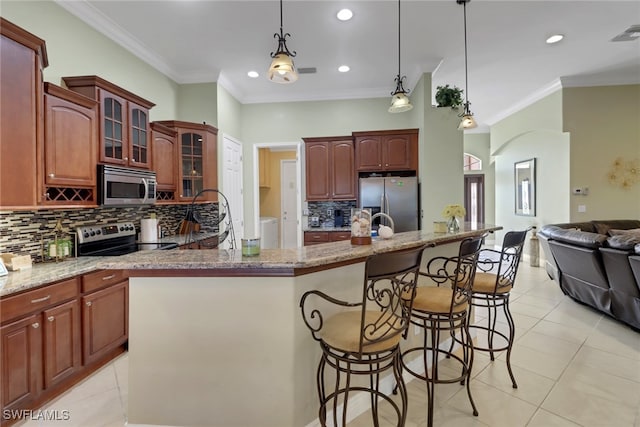 kitchen with a kitchen breakfast bar, a center island with sink, stainless steel appliances, and decorative light fixtures