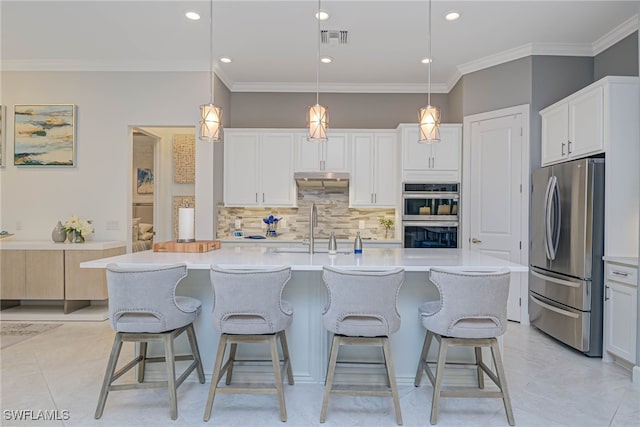 kitchen featuring white cabinets, a kitchen island with sink, stainless steel appliances, and pendant lighting