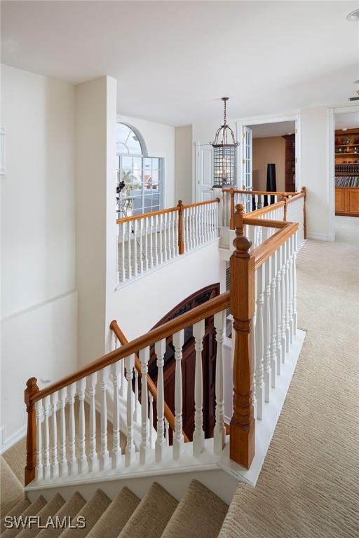 stairs featuring carpet and a notable chandelier