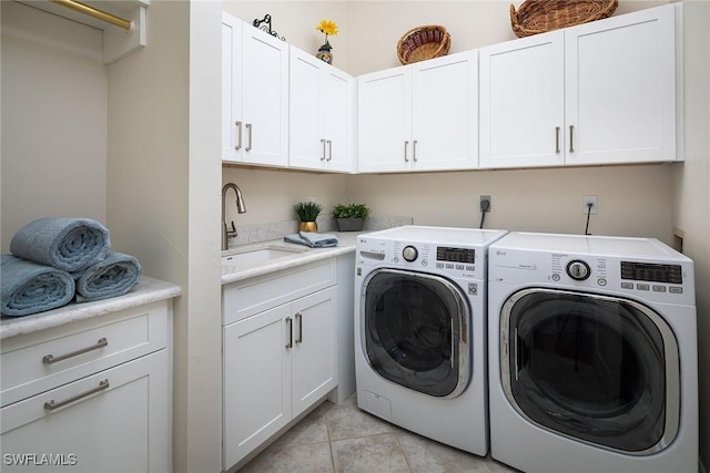 laundry area with washing machine and clothes dryer, sink, light tile patterned floors, and cabinets