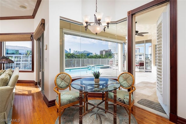 dining room with ceiling fan with notable chandelier, light hardwood / wood-style flooring, and ornamental molding