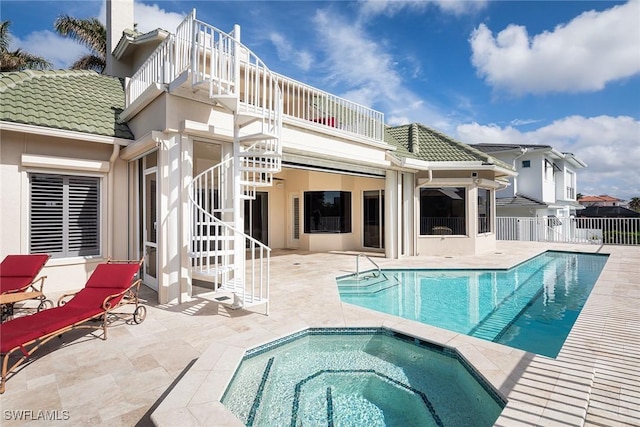 back of property with a swimming pool with hot tub, a balcony, and a patio