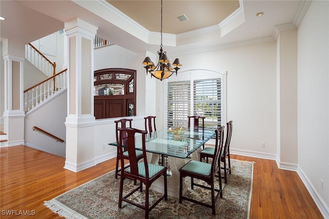 dining space featuring hardwood / wood-style floors, a notable chandelier, crown molding, and a tray ceiling