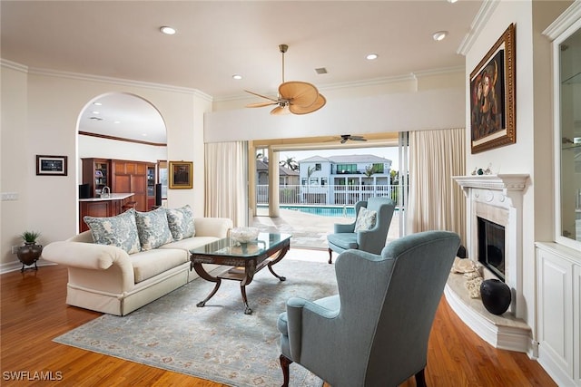 living area featuring baseboards, a high end fireplace, ornamental molding, wood finished floors, and recessed lighting