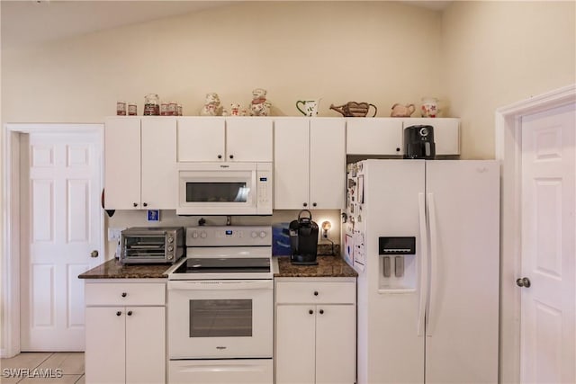 kitchen featuring white cabinetry, light tile patterned floors, white appliances, and dark stone counters