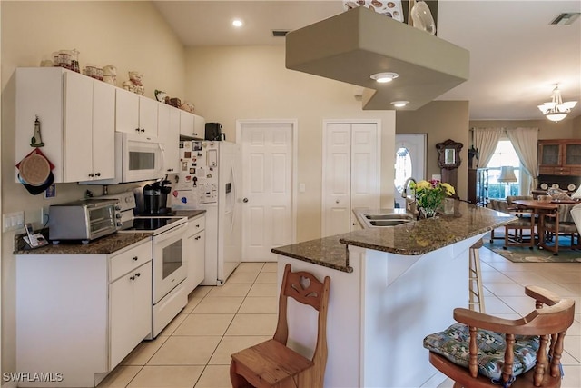 kitchen featuring white appliances, white cabinetry, a breakfast bar area, and light tile patterned flooring