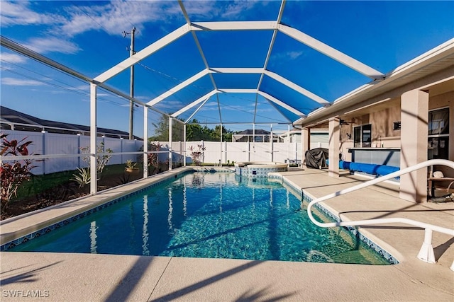 view of swimming pool with glass enclosure, ceiling fan, and a patio area