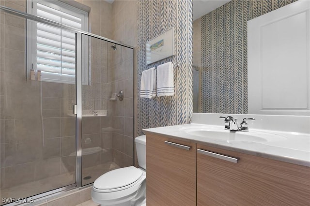 bathroom featuring a shower with door, vanity, and toilet