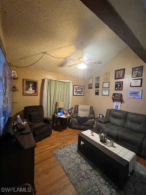 living room featuring vaulted ceiling, ceiling fan, hardwood / wood-style floors, and a textured ceiling