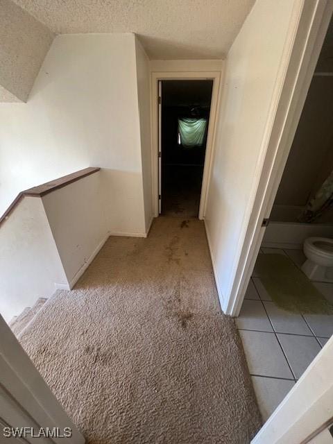 corridor featuring light colored carpet and a textured ceiling