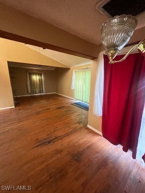 unfurnished room with hardwood / wood-style floors, a textured ceiling, and an inviting chandelier