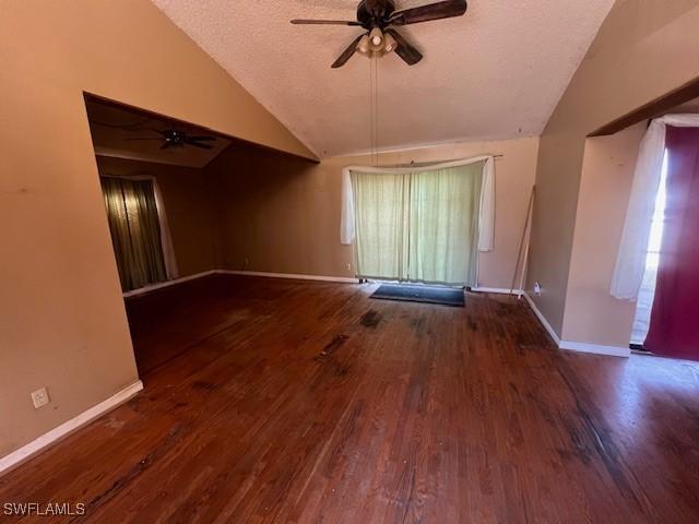 empty room with ceiling fan, dark hardwood / wood-style flooring, a textured ceiling, and vaulted ceiling