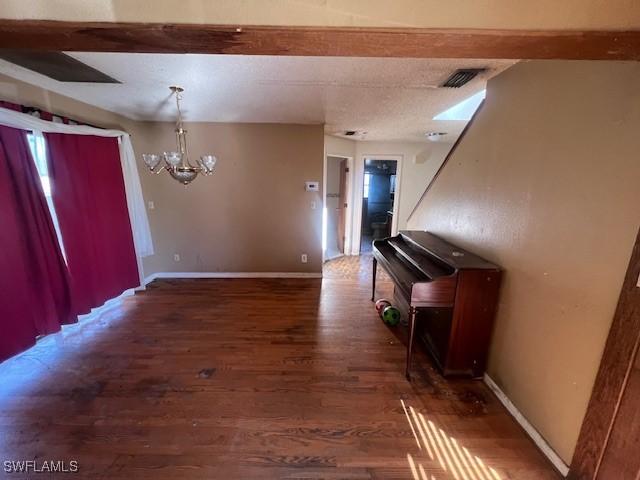 entrance foyer with beam ceiling, dark hardwood / wood-style flooring, and a chandelier