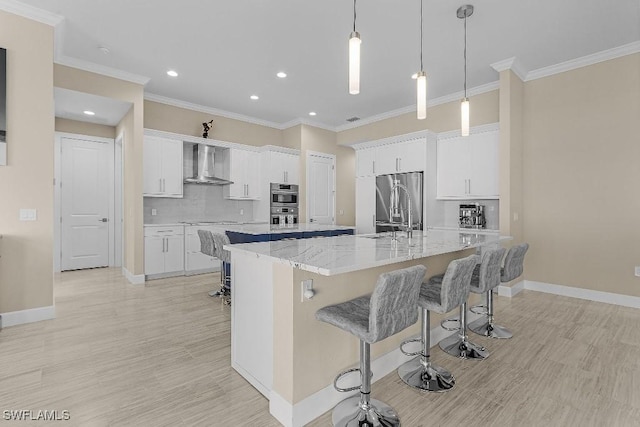 kitchen with white cabinets, sink, wall chimney exhaust hood, appliances with stainless steel finishes, and a large island