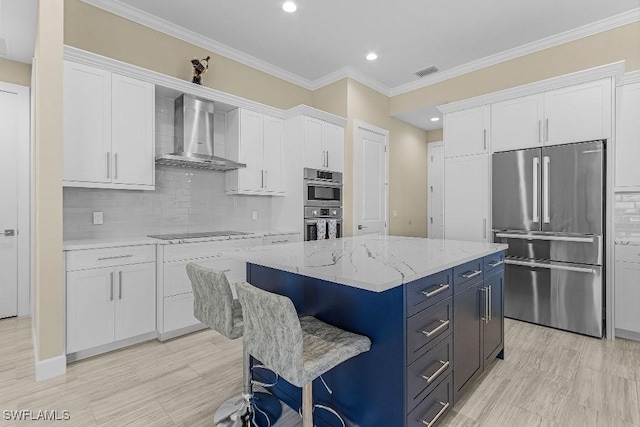 kitchen featuring backsplash, white cabinets, stainless steel appliances, and wall chimney range hood