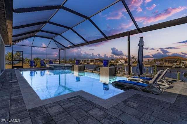 pool at dusk featuring glass enclosure, an in ground hot tub, and a patio