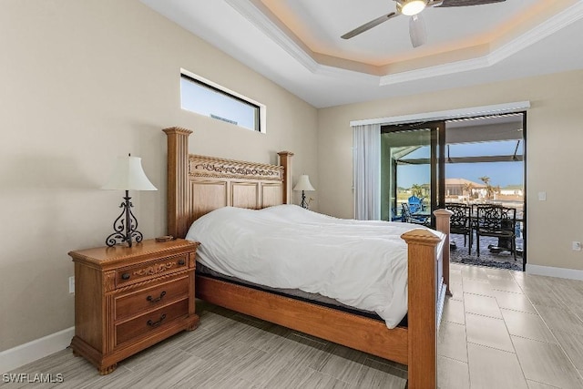 bedroom featuring access to outside, multiple windows, a tray ceiling, and ceiling fan