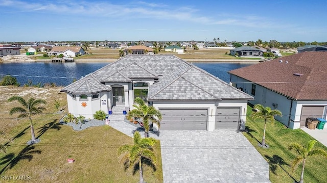 view of front of home featuring a front yard, a water view, and a garage