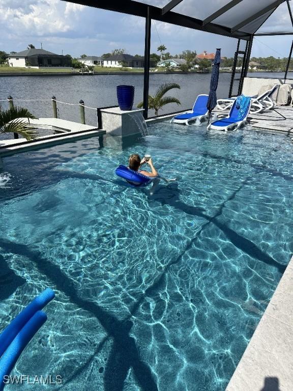 view of pool with pool water feature, a lanai, and a water view