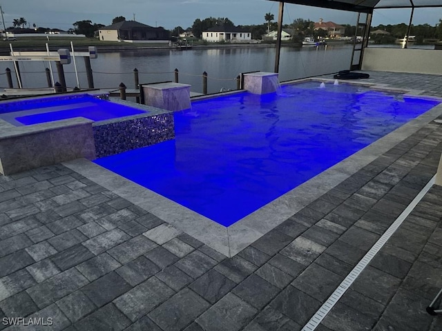 pool at dusk featuring an in ground hot tub and a water view