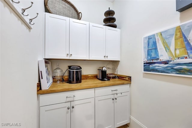 bar featuring white cabinets and wooden counters