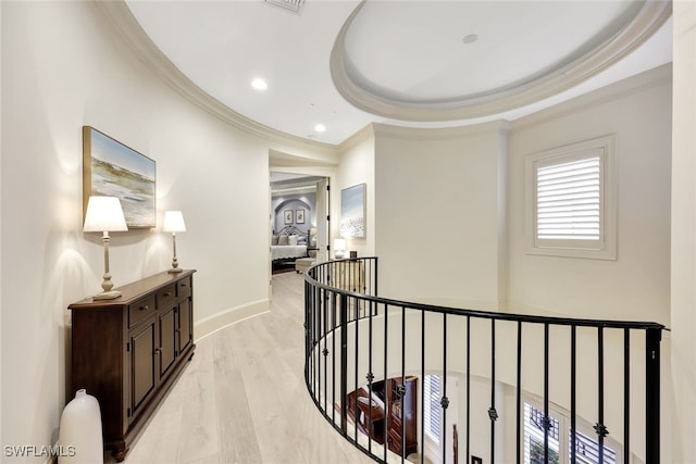 hall with light hardwood / wood-style floors, a tray ceiling, and crown molding