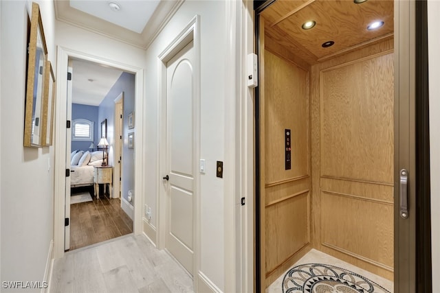 hall featuring elevator, crown molding, and light hardwood / wood-style flooring