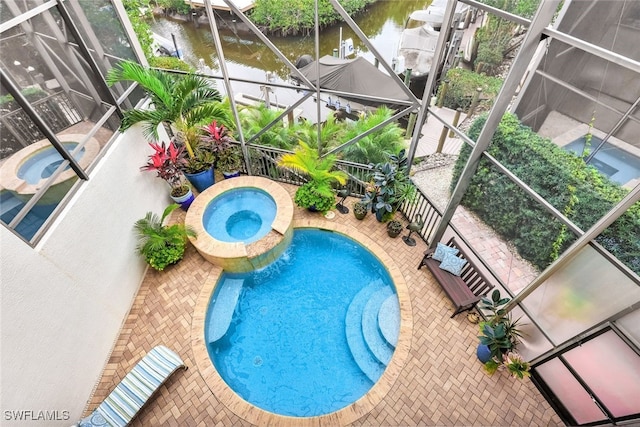 view of pool featuring a water view, a patio area, a lanai, and an in ground hot tub