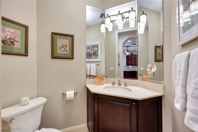 bathroom with toilet, vanity, and ceiling fan