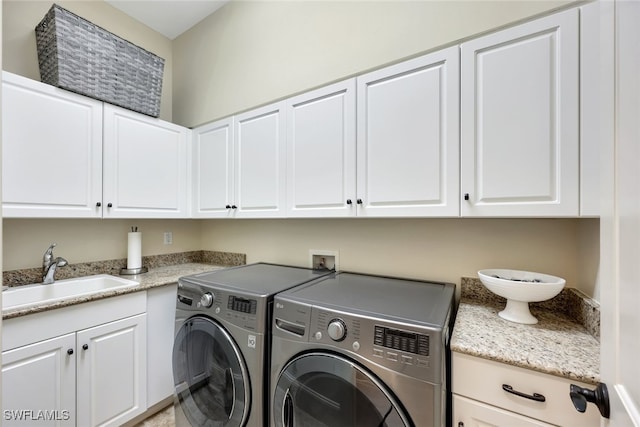 laundry room featuring washer and clothes dryer, sink, and cabinets