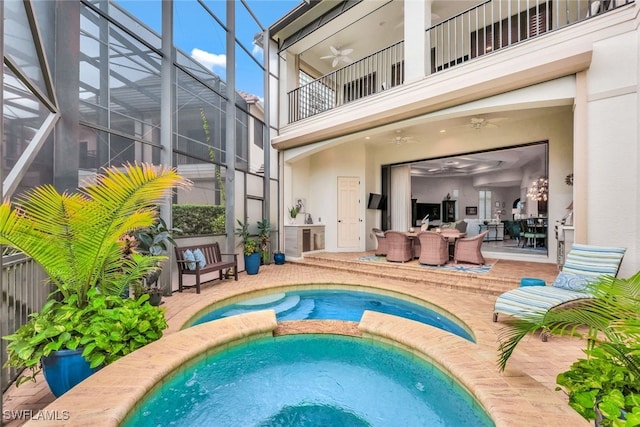 view of pool featuring ceiling fan, glass enclosure, a patio area, and an in ground hot tub