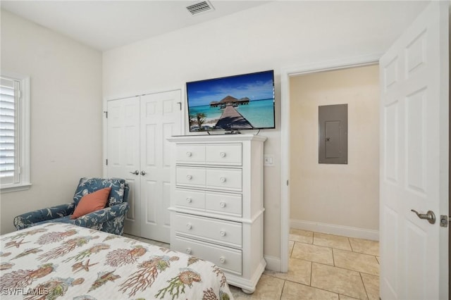 bedroom with light tile patterned floors, electric panel, and a closet