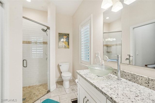 bathroom with tile patterned flooring, vanity, toilet, and walk in shower