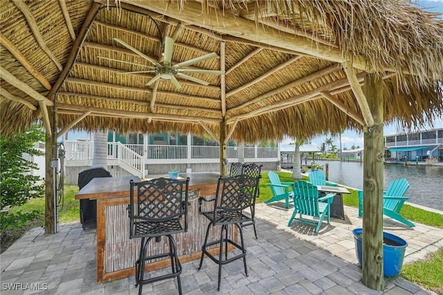 view of patio / terrace featuring a gazebo, ceiling fan, a water view, and exterior bar