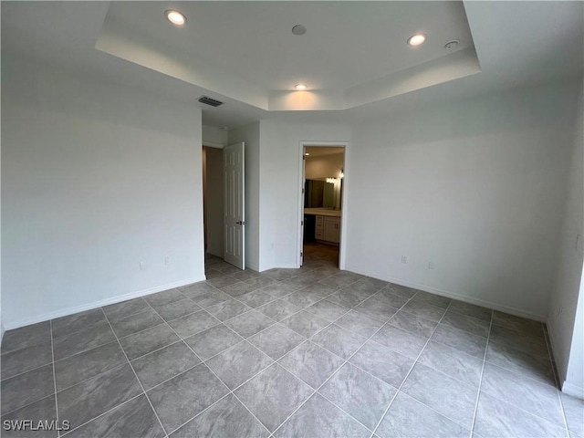 unfurnished room with a tray ceiling and tile patterned floors