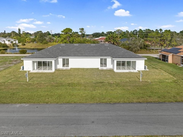 back of property with a lawn and a water view