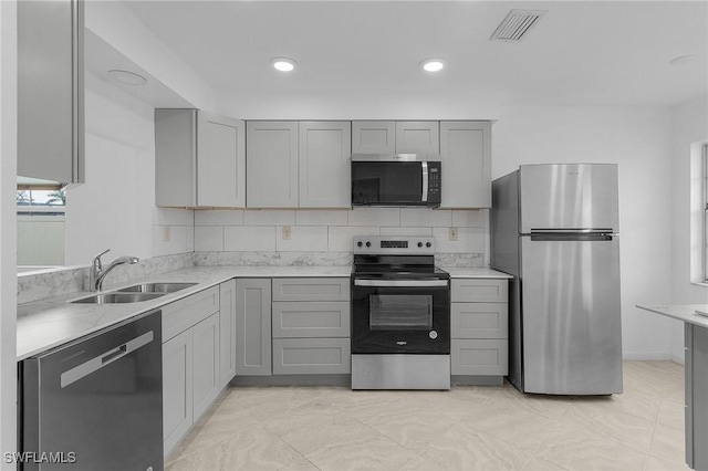 kitchen featuring decorative backsplash, sink, gray cabinetry, and stainless steel appliances