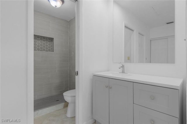 bathroom featuring toilet, vanity, tile patterned flooring, and a tile shower