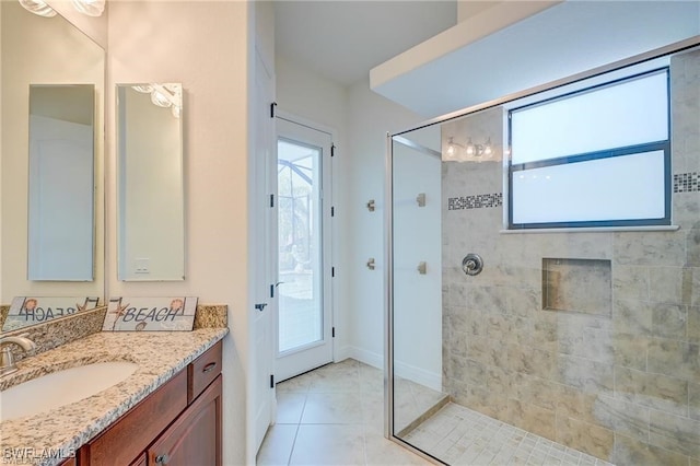 bathroom with a tile shower, tile patterned flooring, vanity, and a healthy amount of sunlight