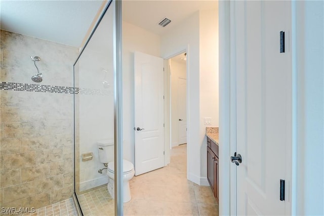 bathroom with toilet, vanity, tile patterned flooring, and tiled shower