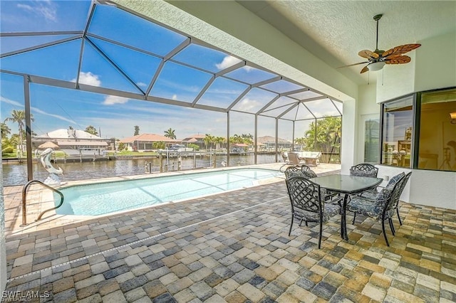 view of pool featuring a water slide, a lanai, a patio area, and a water view