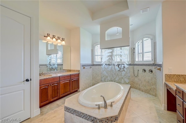 bathroom featuring a healthy amount of sunlight, tile patterned flooring, plus walk in shower, and vanity