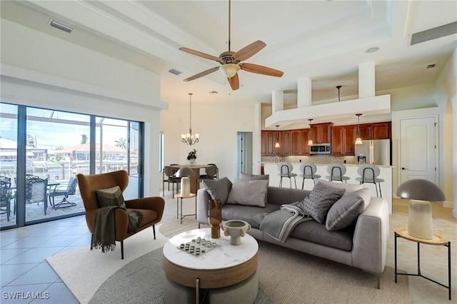 tiled living room with ceiling fan with notable chandelier and a towering ceiling