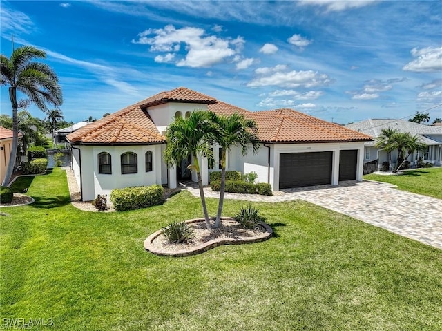 mediterranean / spanish house featuring a garage and a front lawn