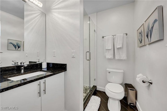 bathroom featuring vanity, toilet, and a shower with door