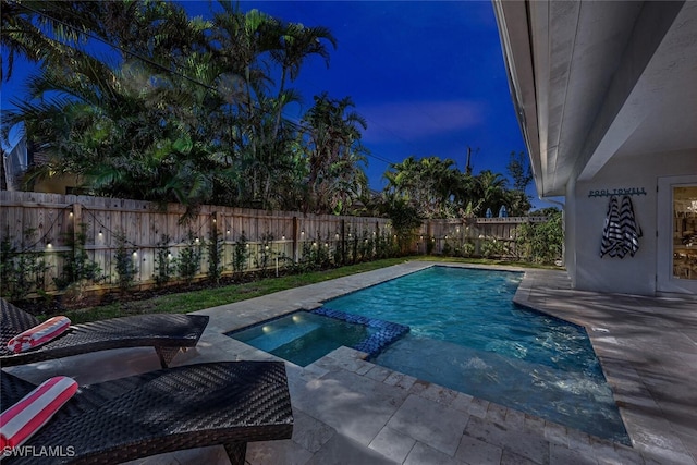 pool at dusk with an in ground hot tub