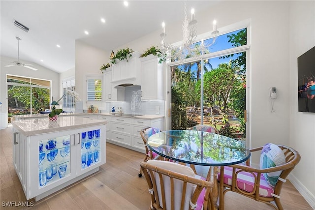 kitchen featuring white cabinets, ceiling fan with notable chandelier, light hardwood / wood-style floors, and backsplash