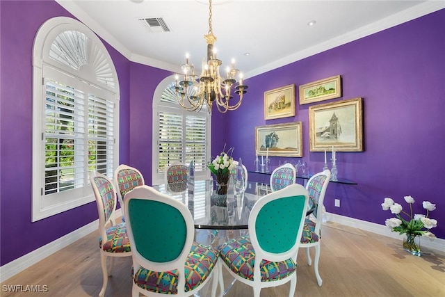 dining room with light wood-type flooring, crown molding, and a notable chandelier