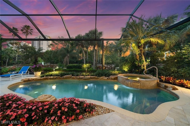 pool at dusk with an in ground hot tub, a patio area, and a lanai