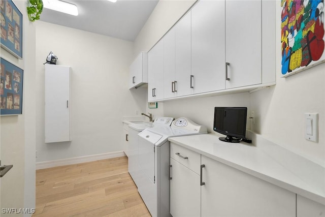 clothes washing area featuring washer and dryer, light hardwood / wood-style floors, and cabinets